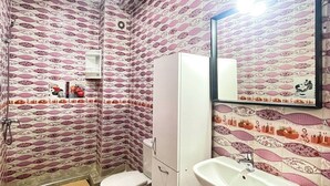 Een badkamer met behang met een patroon, een toilet, een wastafel en een spiegel.