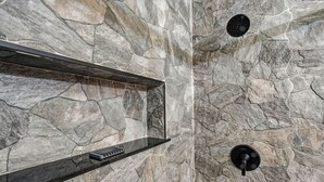 Ein Badezimmer mit Steinwand, Ablagefläche und schwarzem Wasserhahn.
