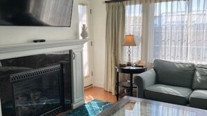 Un salon avec une cheminée, un téléviseur, un canapé et une table basse.