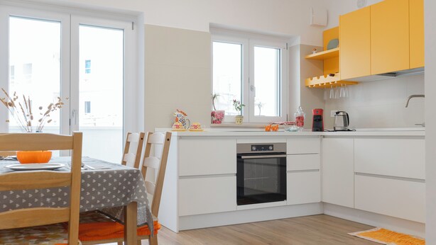 A modern kitchen with white cabinetry, a built-in oven, and a dining area with a table and chairs. - [Prima Classe Apartment] Central Cozy Apartment (Molfetta)