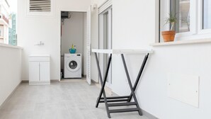 A narrow balcony with a small washing machine, a white cabinet, and a potted plant. - [Prima Classe Apartment] Central Cozy Apartment (Molfetta)