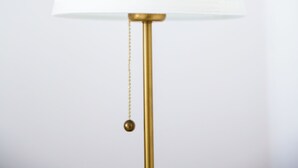 Une lampe avec un abat-jour blanc et un pied doré.