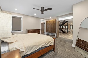 Ein Schlafzimmer mit Bett, Deckenventilator, Holzschränken und einer Treppe zu einer weiteren Ebene.