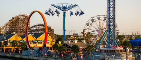 A waterfront amusement park with various rides and a Ferris wheel.