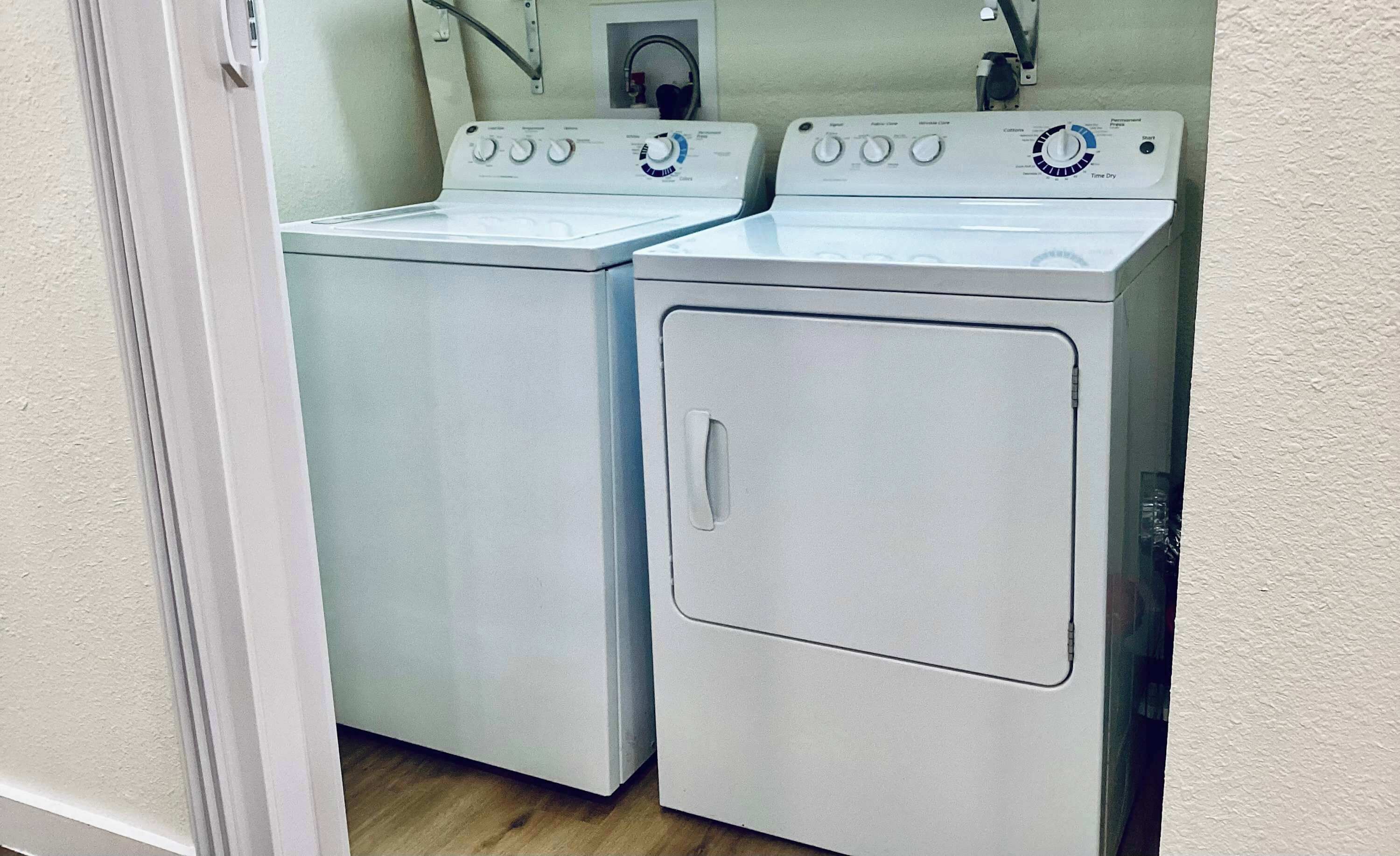 Une buanderie équipée de deux machines à laver à chargement frontal et d’un sèche-linge.