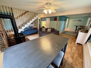 Ein Zimmer mit Esstisch, einer Couch, einer Treppe und einem Deckenventilator.