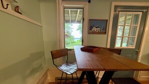 Een eethoek met een houten tafel, twee stoelen, een vloerkleed en een deur met een raam.