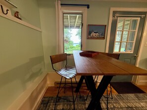 A dining area with a wooden table, two chairs, a rug, and a door with a window. - Pemaquid Trail Gem: Water Views + Huge Deck + Private Beach Access (Bristol)
