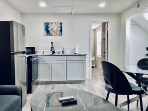 A modern kitchen with a central island, a dining area with a glass table, and a living space with a sofa and a coffee table. - Boardwalk Bungalow 2 Up to 3 (League City)