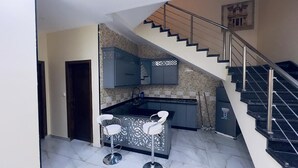A kitchen with a built-in stove, a sink, and a bar area with two stools.