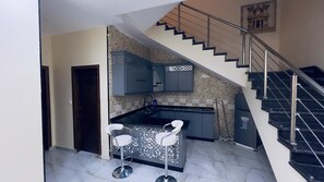 Una cocina con estufa integrada, un fregadero y una barra con dos taburetes.