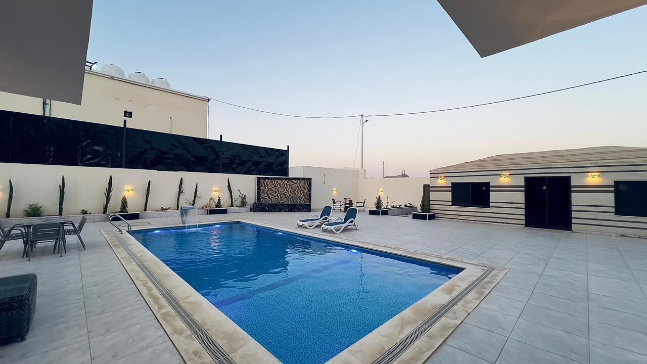 Un área de piscina en la azotea con sillones, una mesita y un muro decorativo.