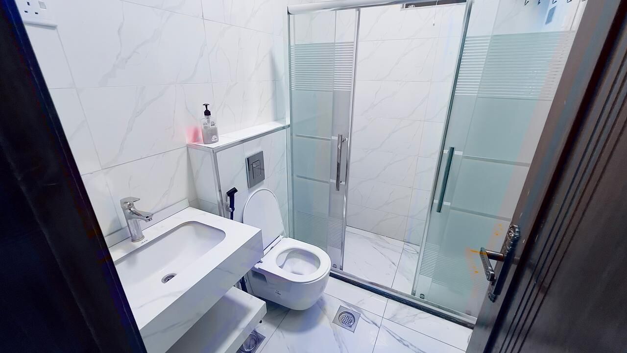 Un baño con inodoro, lavamanos y zona de ducha.