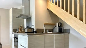 Uma cozinha moderna com forno embutido, micro-ondas e cafeteira sobre a bancada.