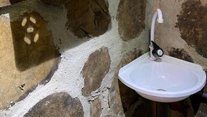 Un muro in pietra con un lavandino bianco e uno specchio sopra.