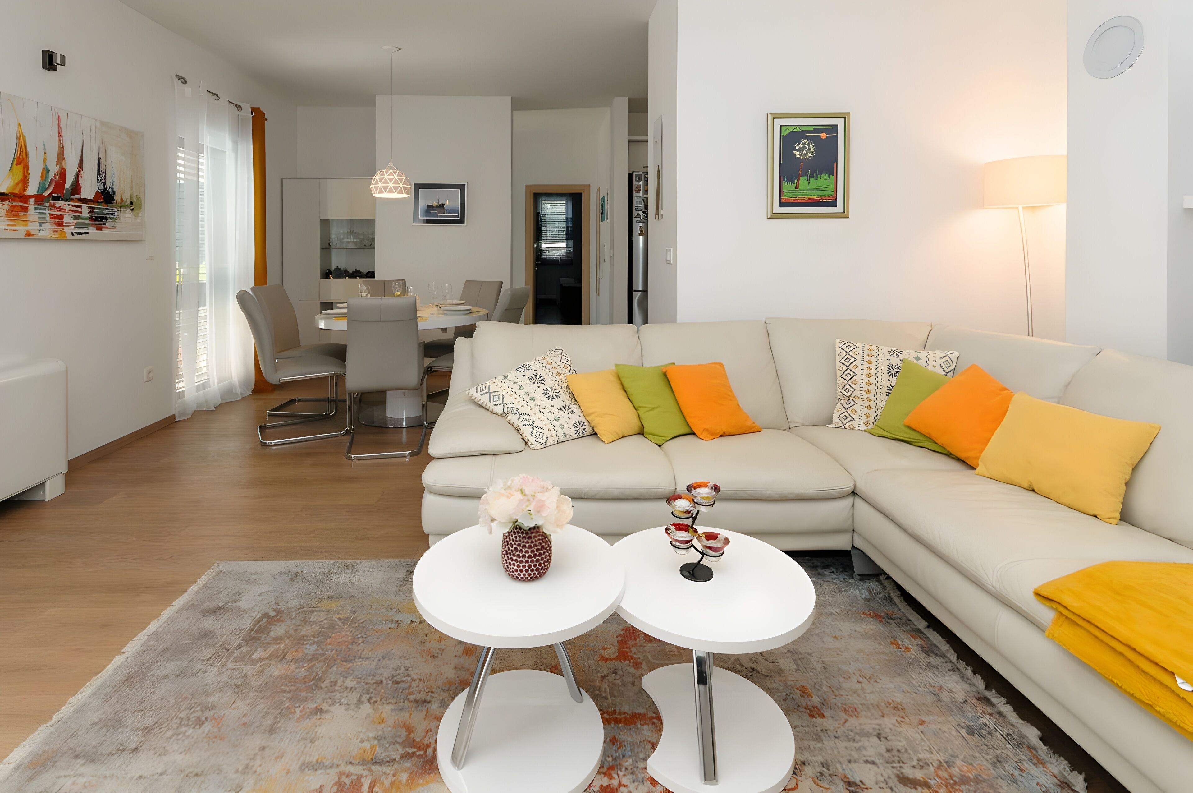 A modern living room with a beige sofa, two white side tables, and a colorful rug.