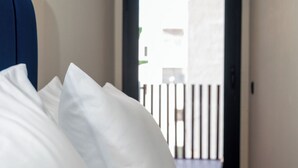 Una cama con sábanas blancas y cabecera azul en una habitación de hotel.