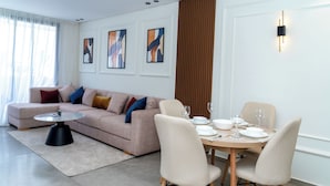 Una sala de estar moderna con un sofá, una mesa redonda para café y un comedor con sillas y una mesa dispuesta para cuatro.