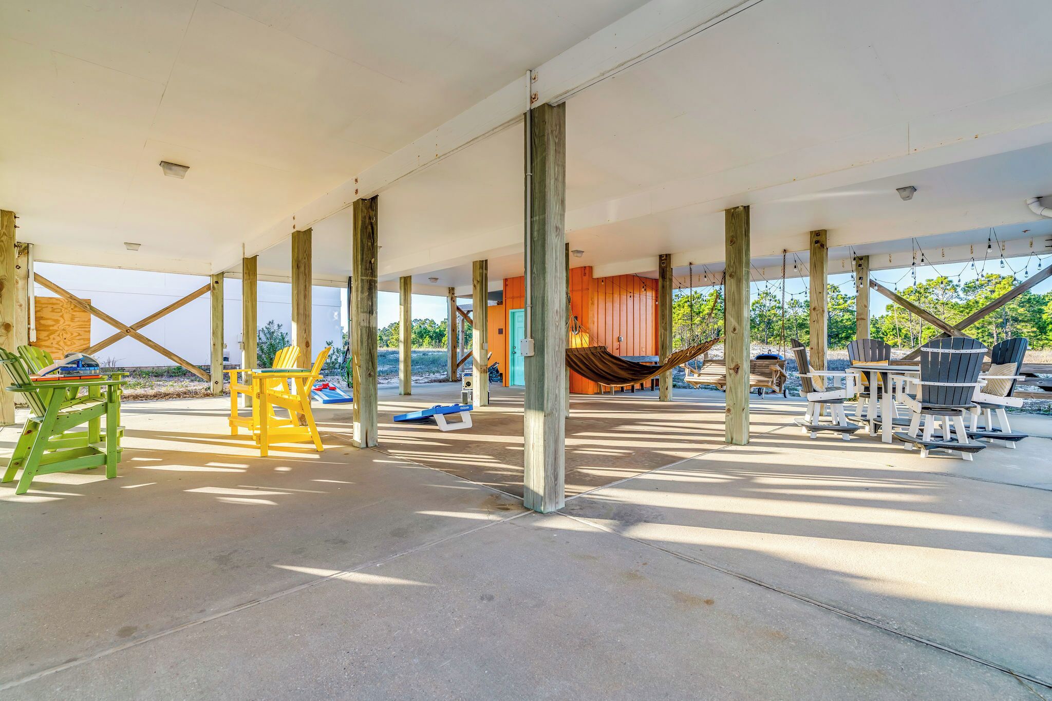 Ein überdachter Patio mit Holzdeckenbalken, Stühlen und einer Hängematte.