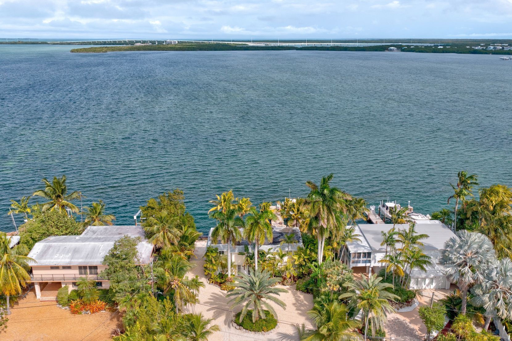 A beachfront property with a sandy beach, palm trees, and a view of the ocean.
