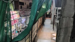 A narrow alleyway with a green netting on one side, a tiled floor, and a metal railing. - Shree Radhe Krishna Guest House (Jhansi)