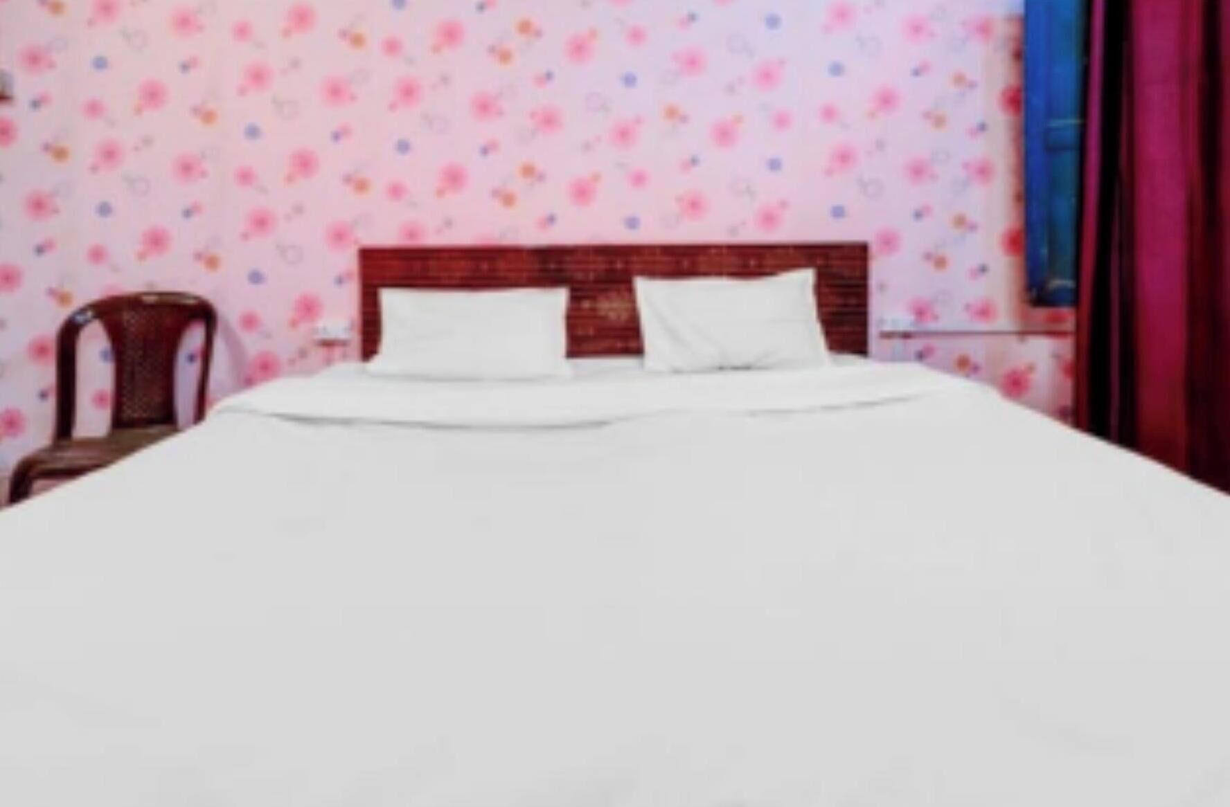 A bed with white bedding in a room with floral wallpaper.