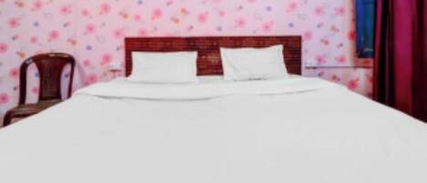A bed with white bedding in a room with floral wallpaper.