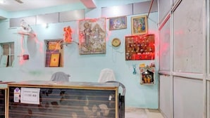 A room with a reception desk, a clock, framed artwork, and religious statues. - Shree Radhe Krishna Guest House (Jhansi)
