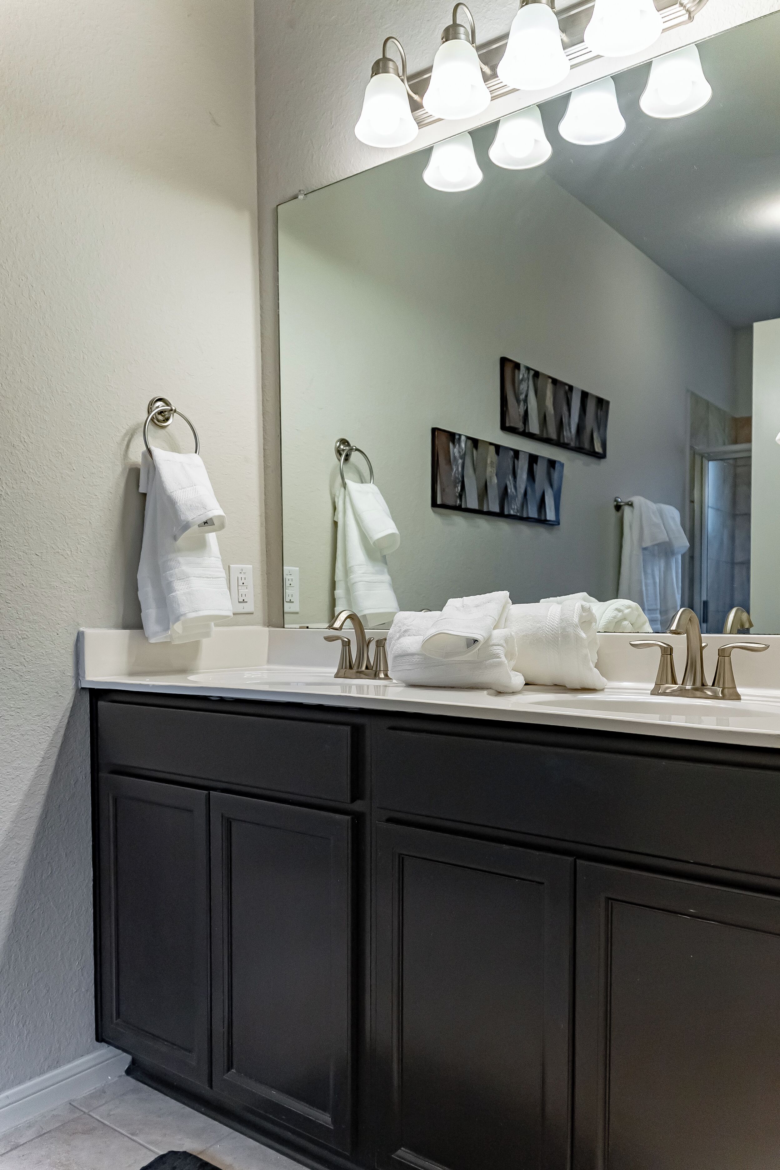 A bathroom with a large mirror, two sinks, and a towel rack.