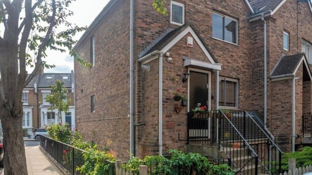 A two-story brick house with a front door, a small porch, and a wooden fence. -  1 bedroom 1 bathroom apartment in a quiet street in the heart of Chelsea, (London)