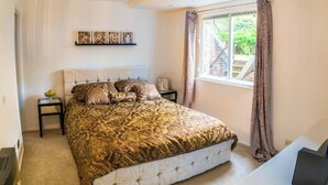 A bedroom with a bed, a nightstand, a window with curtains, and a wall-mounted shelf with artwork. -  1 bedroom 1 bathroom apartment in a quiet street in the heart of Chelsea, (London)