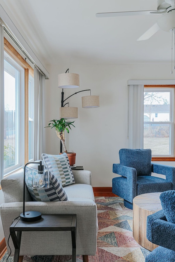 A living room with a sofa, a blue armchair, a coffee table, a lamp, a floor lamp, and a potted plant.
