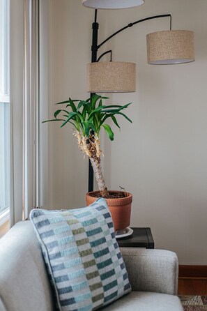 Una planta en maceta sobre una mesita junto a un sofá con cojín a rayas.