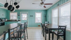 A kitchen with teal walls, a dining table, chairs, a ceiling fan, and hanging pots. - Millhouse: Private Pool Dog Friendly Fenced Yard (Staunton)