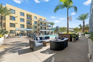 A hotel courtyard with a pool, outdoor seating, and palm trees. - Endless Summer: Luxe 1BR w/ Resort-Style Amenities (San Diego)