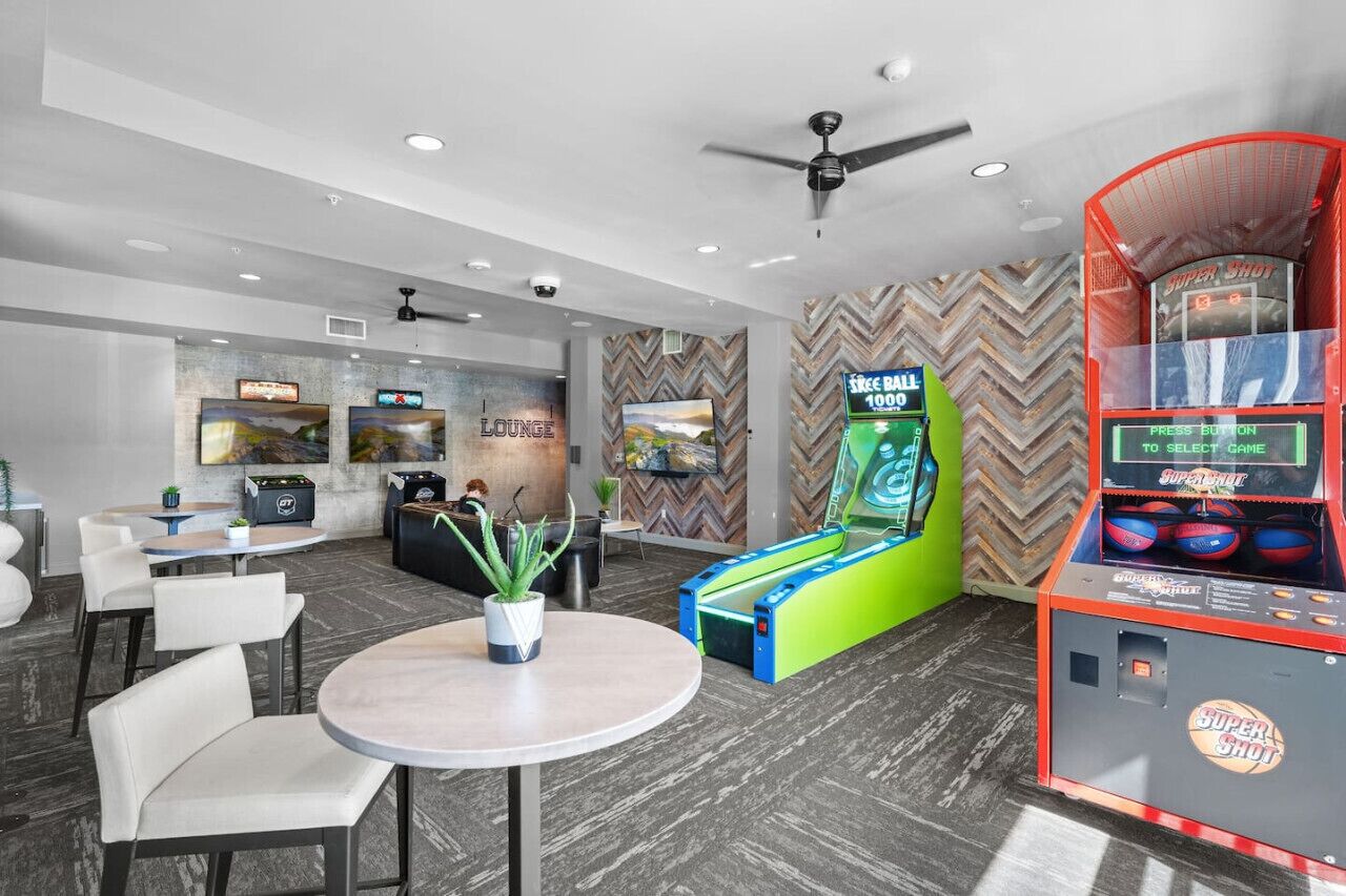 Un área de estar moderna con dardos, una máquina de juegos Super Shot y una mesa de billar.