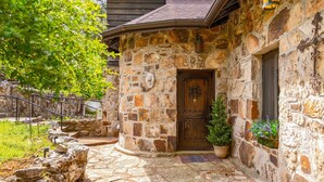 A stone building with a wooden door, a stone staircase, and a potted plant. - Lake Views • 4 Kings • Hot Tub • Game Room (Forsyth)