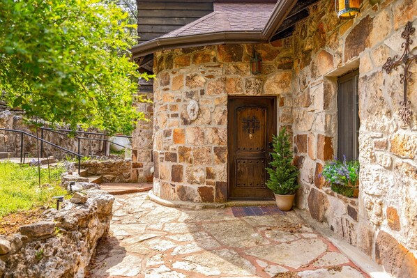 A stone building with a wooden door, a stone staircase, and a potted plant.