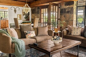 A cozy living room with a brown sofa, a wooden coffee table, and a chandelier.