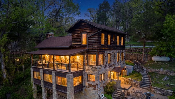 A multi-story log cabin with stone foundations, a balcony, and a stone staircase leading to a deck. - Lake Views • 4 Kings • Hot Tub • Game Room (Forsyth)