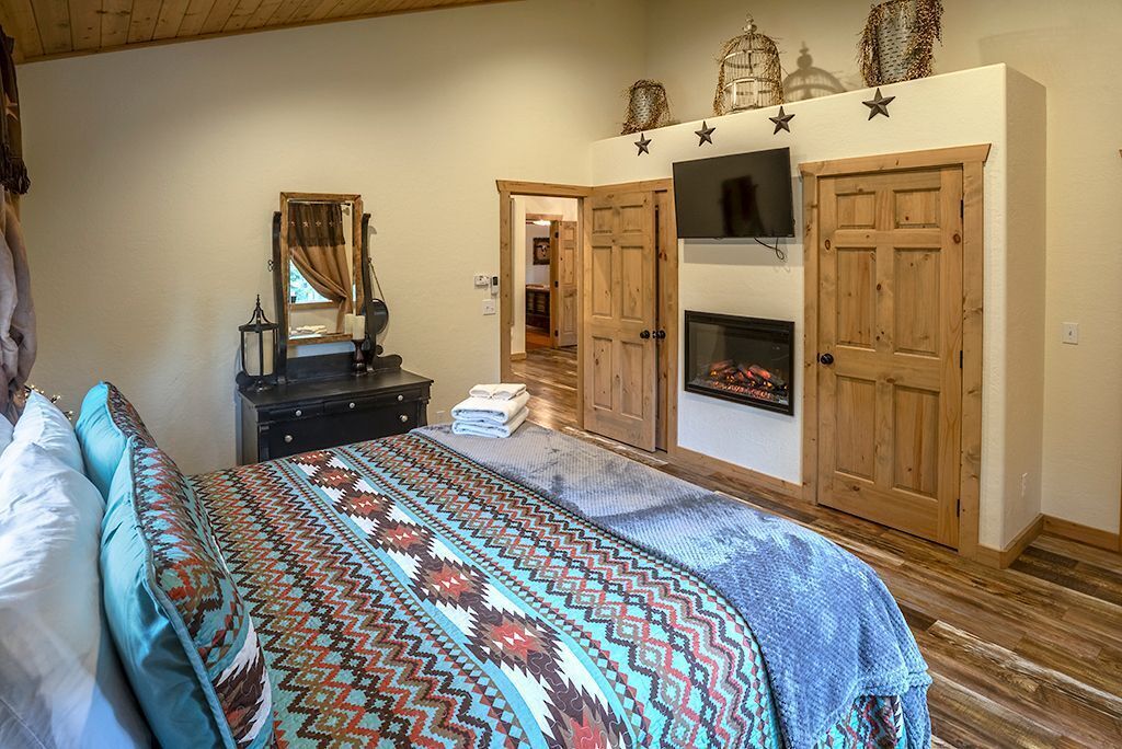 Une chambre à coucher avec un lit, une commode, un miroir et une cheminée.