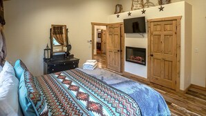 A bedroom with a bed, dresser, mirror, and a fireplace. - Peaceful Wallowa Lake Cabin Near State Park (Joseph)
