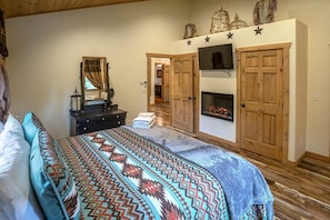 Un dormitorio con cama, cómoda, espejo y chimenea.