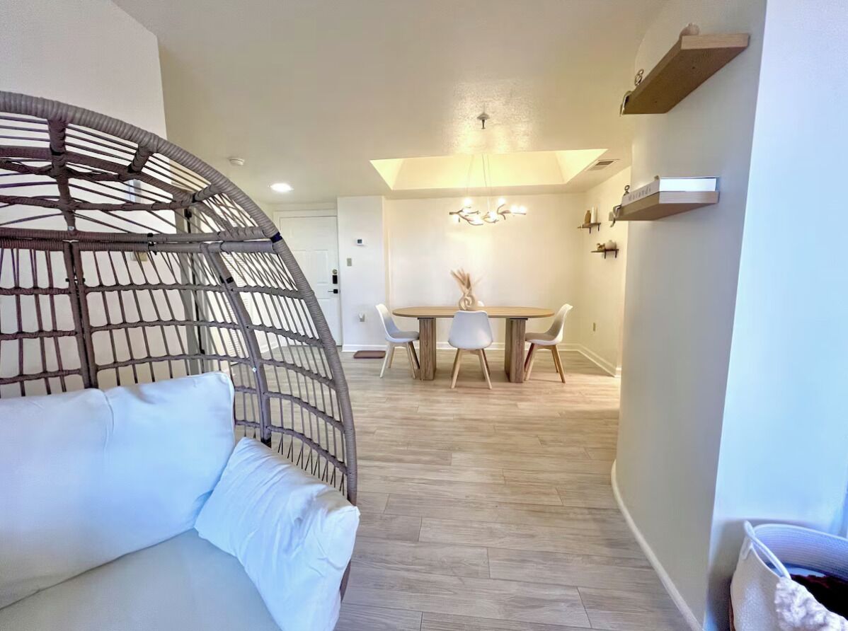 A modern interior with a round dining table, white chairs, and a hanging chair.