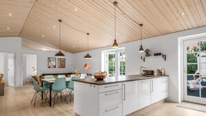 Une cuisine spacieuse dotée d’un grand îlot central, de luminaires suspendus et offrant une vue sur l’extérieur.