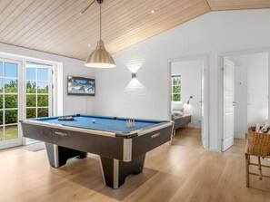 Une table de billard dans une pièce dotée d’un plafond en bois et d’une grande fenêtre.