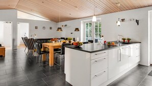 A modern kitchen with white cabinets, a black countertop, and a wooden ceiling. - "Sod" - 3.2km from the sea by Interhome (Blåvand)