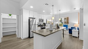 Una cocina moderna con armarios blancos, electrodomésticos de acero inoxidable y una isla central.