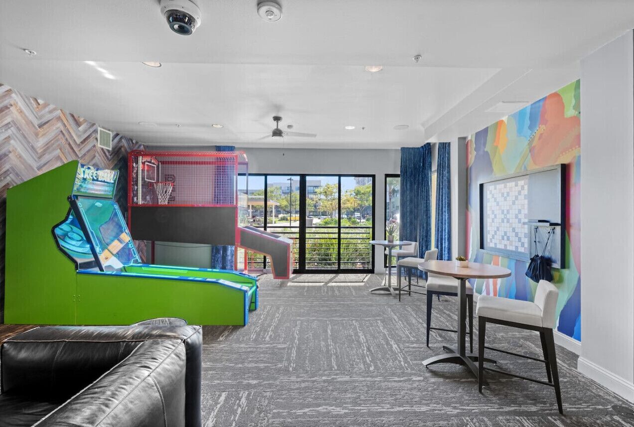 A modern room with a green and black sofa, a small table, and a colorful mural.
