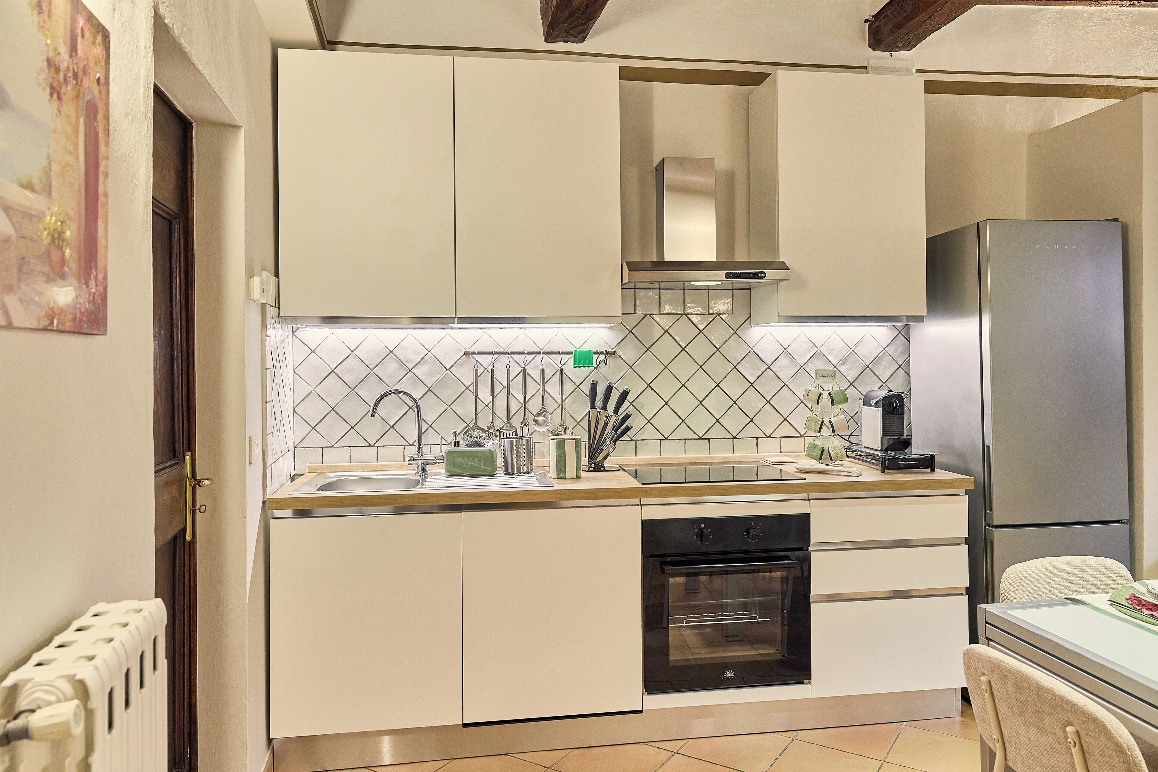 A modern kitchen with white cabinetry, a stainless steel refrigerator, and a tiled backsplash.